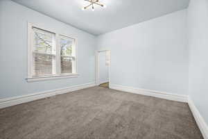 Empty room featuring carpet flooring and a chandelier