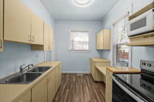 Kitchen with electric range, ornamental molding, white microwave, light countertops, and dark wood finished floors