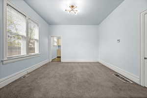 Unfurnished bedroom with dark carpet and hanging lights