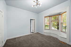 Unfurnished room featuring dark carpet and hanging lights