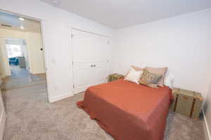 Bedroom with light carpet and a closet