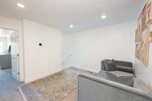 Living area with an upstairs landing, carpet flooring, and recessed lighting