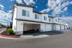 View of side of home featuring an attached garage, a residential view, and stucco siding