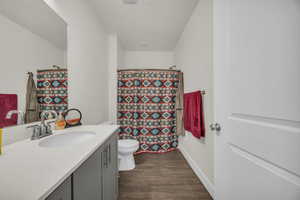 Full bath with vanity, curtained shower, and dark wood-style flooring