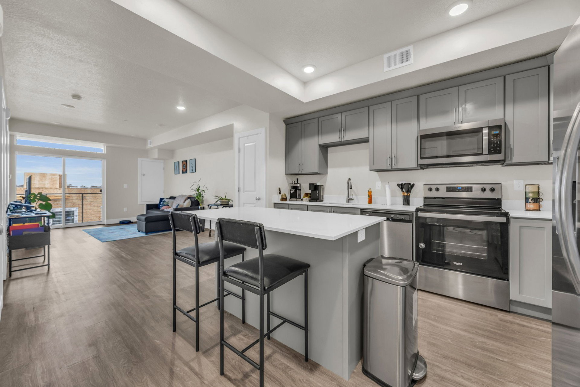 Kitchen featuring gray cabinetry, stainless steel appliances, open floor plan, a breakfast bar, and light wood-style floors