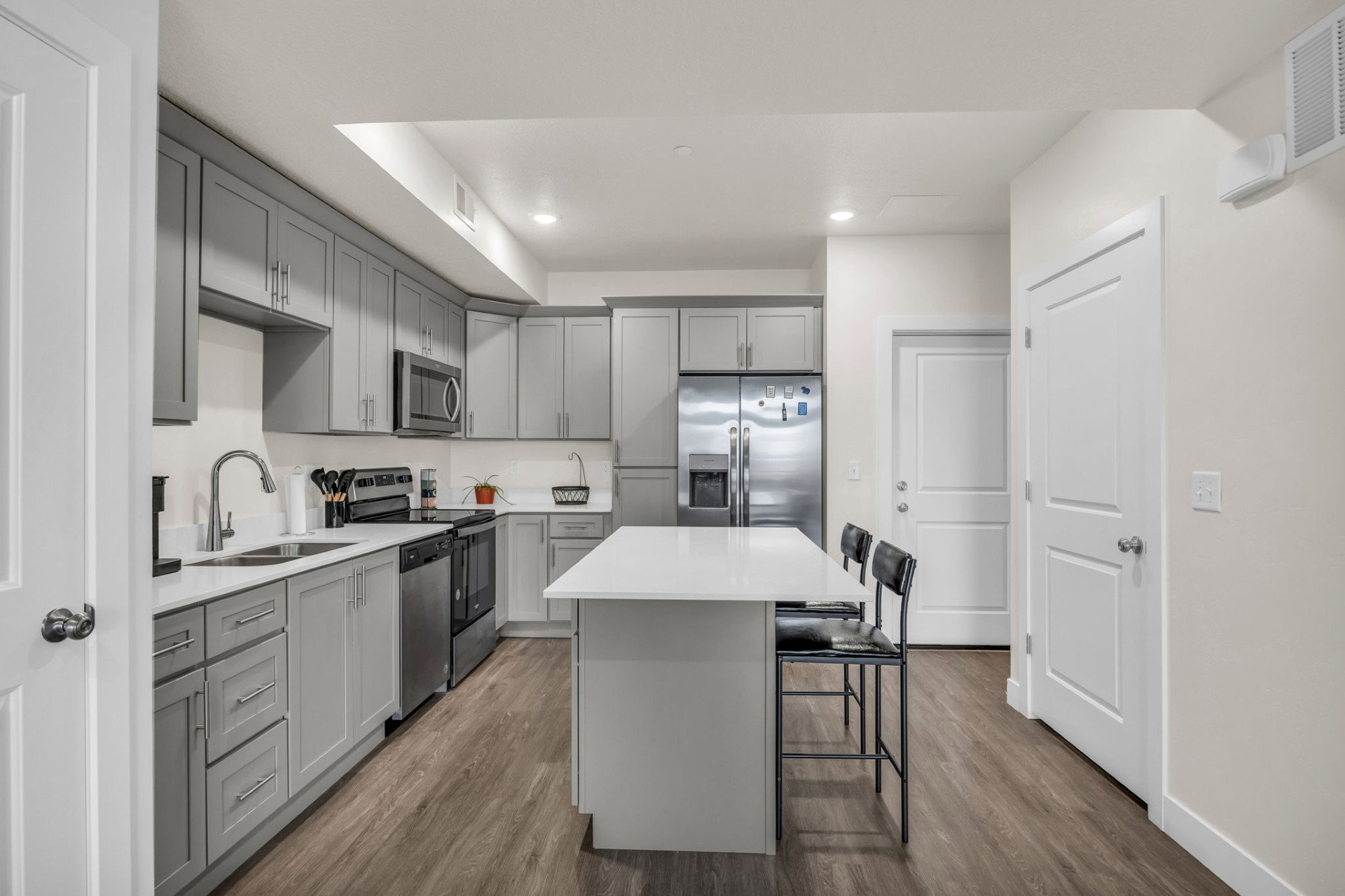 Kitchen featuring gray cabinetry, a center island, dark wood-type flooring, a kitchen bar, and recessed lighting