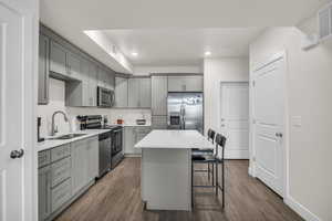 Kitchen featuring gray cabinetry, a center island, dark wood-type flooring, a kitchen bar, and recessed lighting