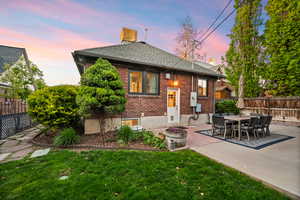 Rear view of house featuring brick siding, a patio, outdoor dining area, and a chimney