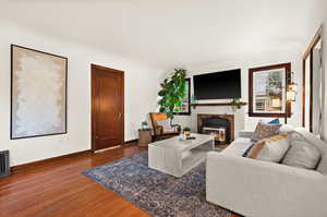 Living room featuring a glass covered fireplace and dark wood-type flooring