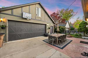 Property exterior at dusk featuring outdoor dining area, a garage, stucco siding, and a patio