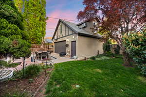 Back of property featuring a shingled roof, a fenced backyard, stucco siding, a garage, and outdoor dining space