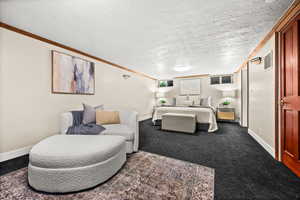 Bedroom with crown molding, a textured ceiling, and carpet