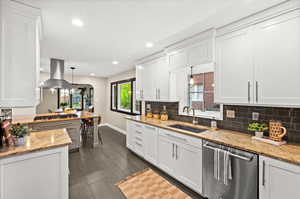 Kitchen with white cabinetry, stainless steel appliances, light stone counters, and pendant lighting