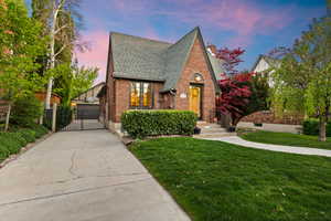 English style home with brick siding, a shingled roof, a lawn, and a chimney