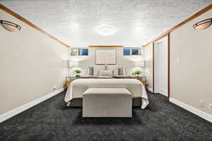 Bedroom with ornamental molding, a textured ceiling, and carpet