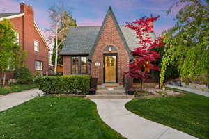 Tudor home with a yard, brick siding, and a shingled roof