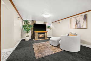 Living area featuring a glass covered fireplace, a textured ceiling, carpet, and ornamental molding