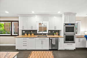 Kitchen with healthy amount of natural light, stainless steel appliances, white cabinets, light stone countertops, and recessed lighting
