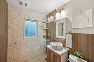 Full bath featuring vanity, a walk in shower, and wainscoting