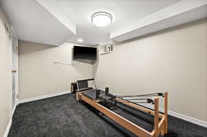 Exercise room featuring dark colored carpet and baseboards