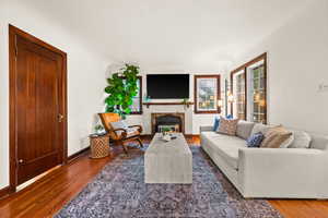 Living room with wood finished floors and a glass covered fireplace