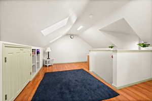Additional living space featuring a skylight, light wood-type flooring, and a textured ceiling