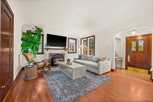 Living area with wood-type flooring, arched walkways, and a glass covered fireplace