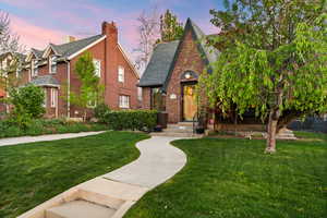 English style home with a front lawn, brick siding, and a shingled roof