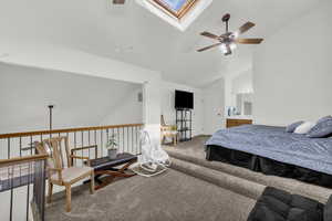 Carpeted bedroom with a skylight, lofted ceiling, and a ceiling fan