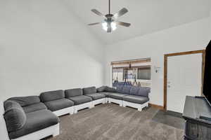 Living area with ceiling fan, vaulted ceiling, and stone finish floors