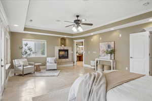 Bedroom featuring crown molding, a tray ceiling, a ceiling fan, recessed lighting, and a multi sided fireplace