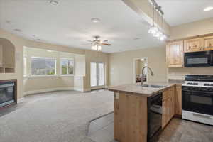 Kitchen featuring black appliances, open floor plan, a peninsula, light wood finish cabinets, and light tile patterned flooring