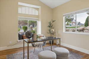 Home office featuring light wood finished floors, healthy amount of natural light, and vaulted ceiling
