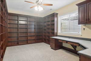 Unfurnished office featuring light carpet, ceiling fan, and built in study area