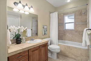 Bathroom featuring vanity, tiled shower / bath, tasteful backsplash, and light tile patterned floors