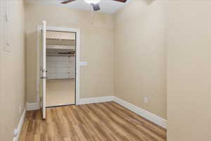 Unfurnished bedroom with light wood-style floors, a ceiling fan, and a spacious closet