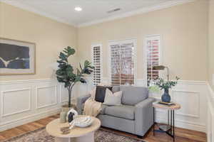 Sitting room with ornamental molding, wood finished floors, a wainscoted wall, a decorative wall, and recessed lighting