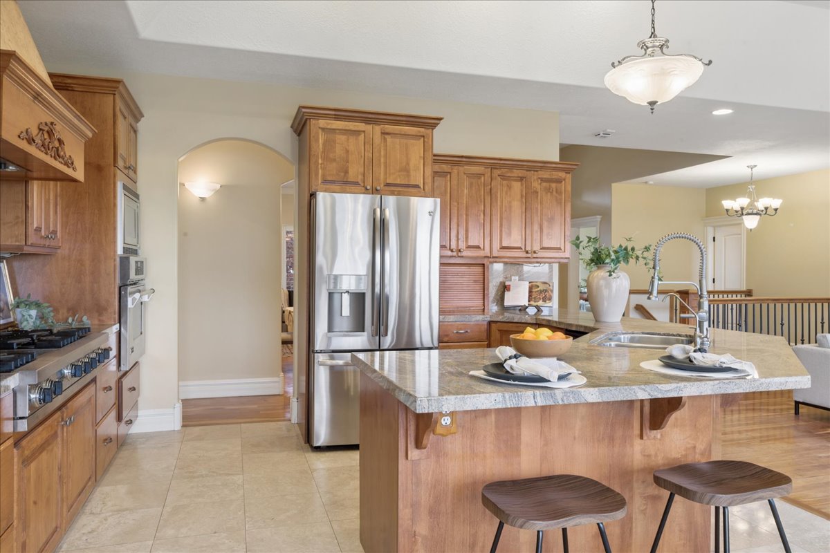 Kitchen featuring wood finish cabinetry, a breakfast bar area, stainless steel appliances, a peninsula, and arched walkways
