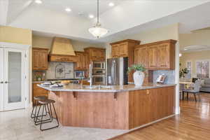 Kitchen with wood finish cabinets, a breakfast bar, stainless steel appliances, backsplash, and arched walkways