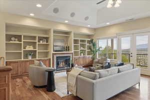 Living area with recessed lighting, french doors, light wood-style floors, a glass covered fireplace, and built in features