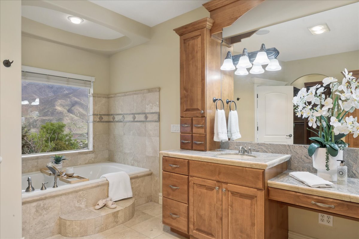 Bathroom featuring vanity, a bath, and light tile patterned floors