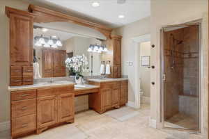 Bathroom with double vanity, a shower stall, light tile patterned floors, and recessed lighting