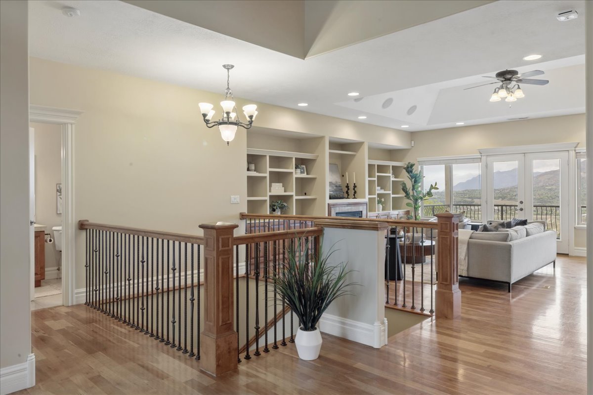 Hallway featuring wood finished floors, an upstairs landing, french doors, built in shelves, and suspended lighting