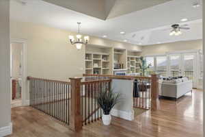 Hallway featuring wood finished floors, an upstairs landing, french doors, built in shelves, and suspended lighting