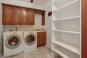 Laundry room featuring light tile patterned floors, cabinet space, washing machine and dryer, and ceiling fan