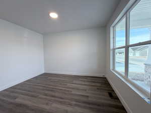 Unfurnished room featuring dark wood finished floors and baseboards