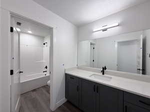 Full bath featuring vanity, dark wood-style flooring, shower / bathtub combination, and a textured ceiling