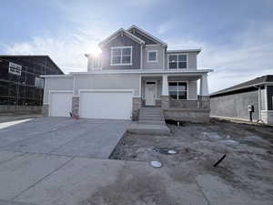 Craftsman-style home with stone siding, a porch, concrete driveway, a garage, and board and batten siding