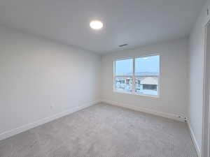 Unfurnished room featuring light carpet and baseboards