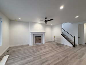 Unfurnished living room with ceiling fan, light wood finished floors, recessed lighting, and a fireplace